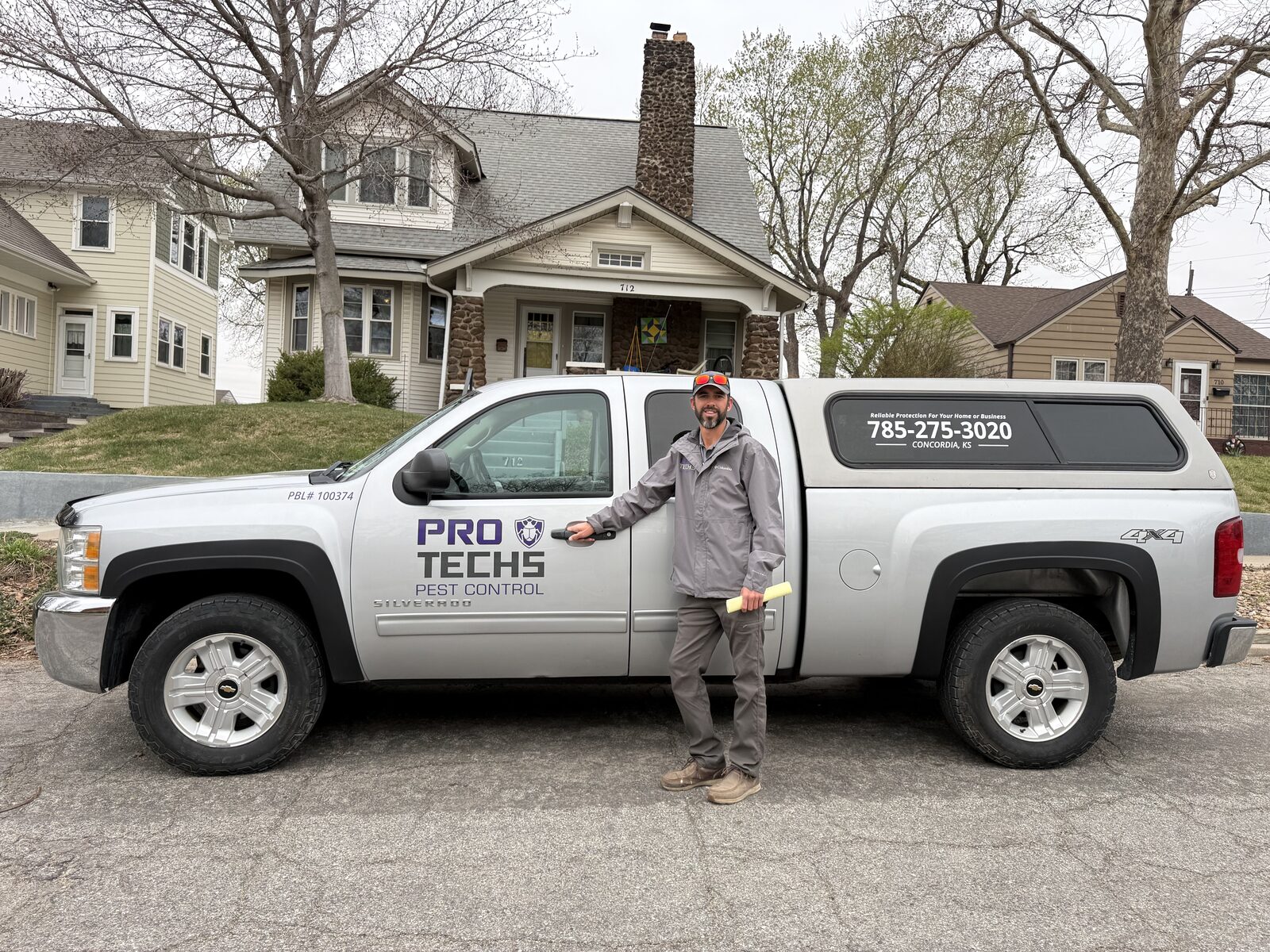 Pro Techs Pest Control technician beside the company truck at a customer's home